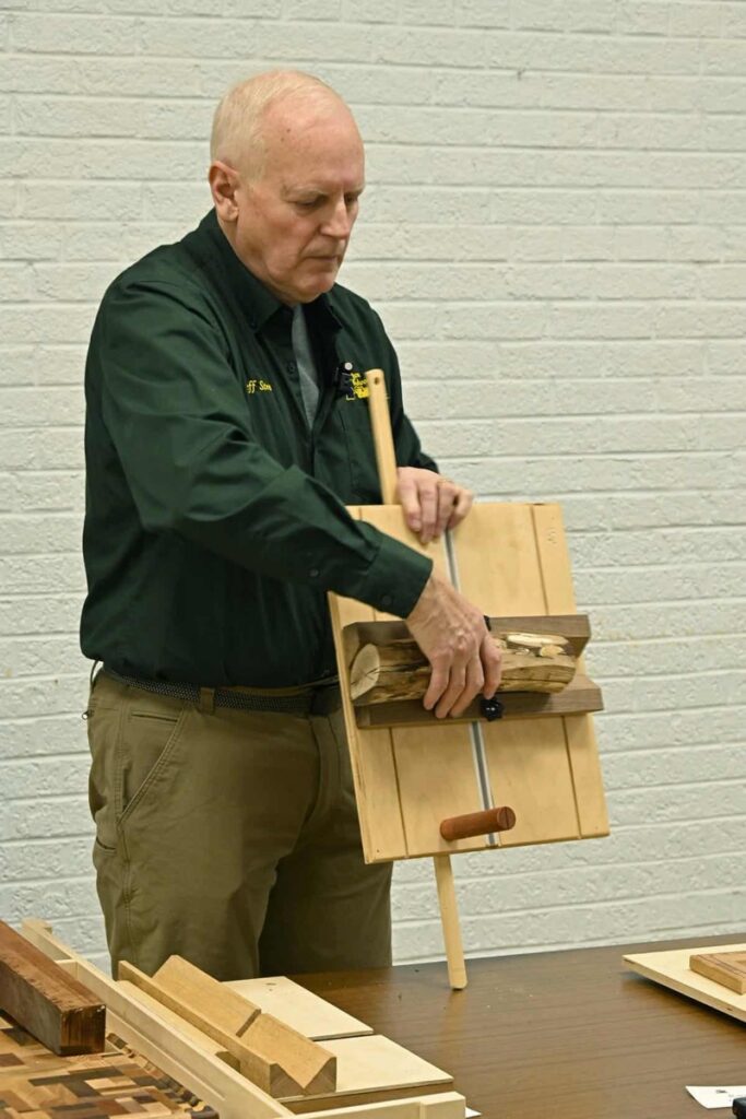 A member demonstrates a woodworking jig to the group at a meeting.